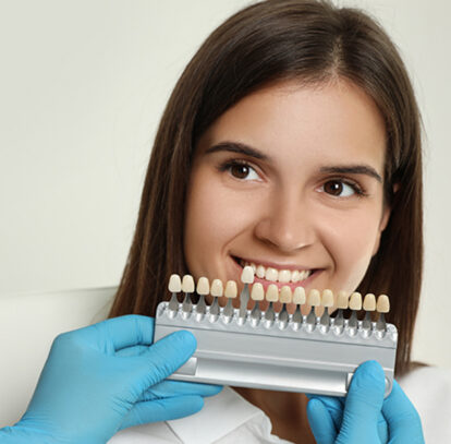 Girl holding tooth veneers model of Hamilton dental clinic