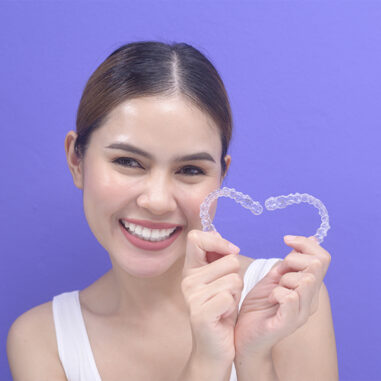 Girl holding a clear aligners for straighten her teeth